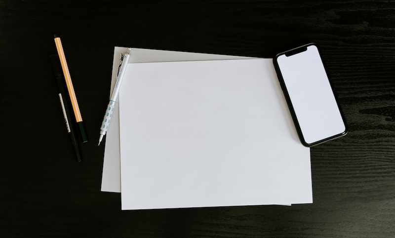 Ein Blatt Papier, ein Stift und ein Smartphone um die Kontakte anzurufen