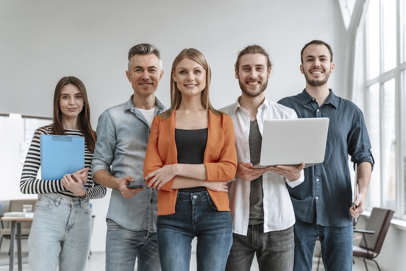 Eine Gruppe von Arbeitskollegen, die freundlich in die Kamera schaut.