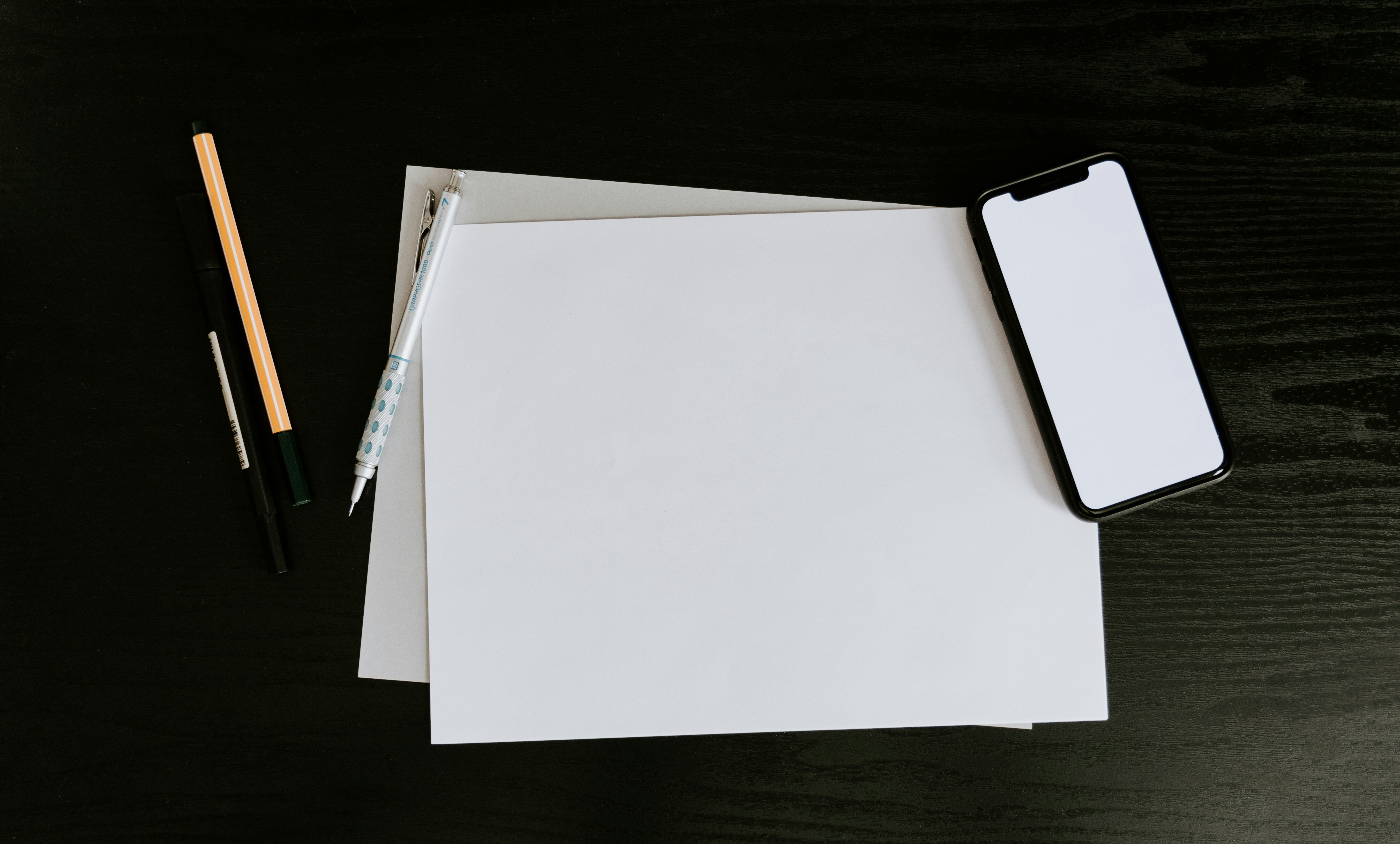 Ein weisses Blatt Papier mit Stift und einem Smartphone